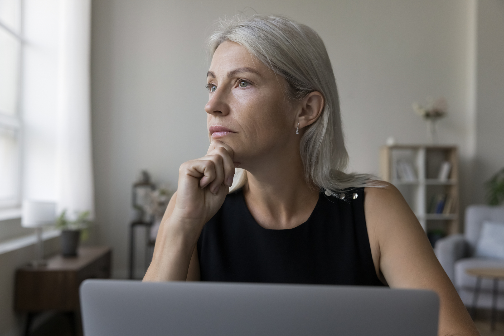 Vrouw zit achter laptop, onzeker over oplichters
