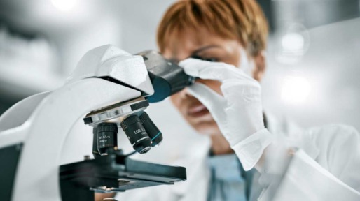 Vrouw kijkt in microscoop