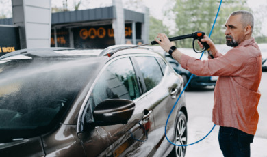 oudere man wast zijn auto bij wasbox