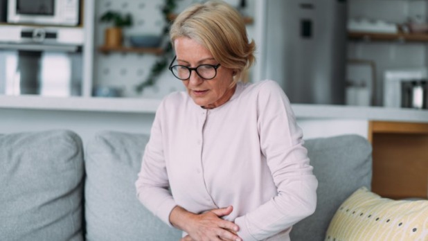 Vrouw met handen op haar buik vanwege pijn