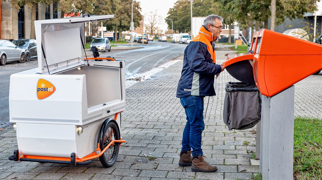 Postbezorger leegt oranje brievenbus