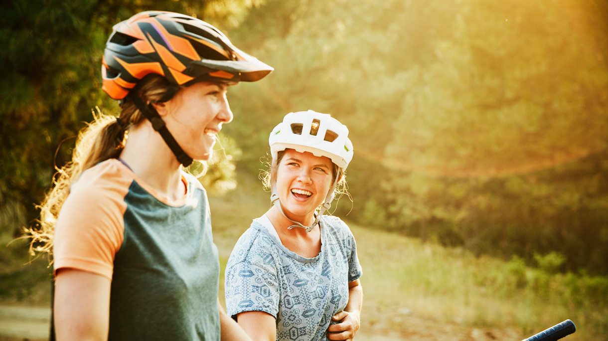 Twee vrouwen op de fiets in de zomer met een fietshelm op
