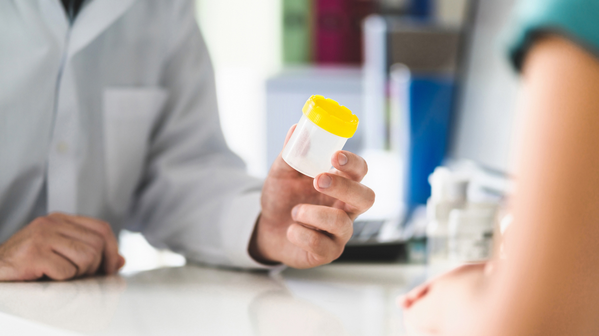 Arts geeft potje voor urine aan patiënt