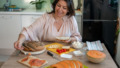 Vrouw eet gezonde en lekkere maaltijd met zalm aan keukentafel