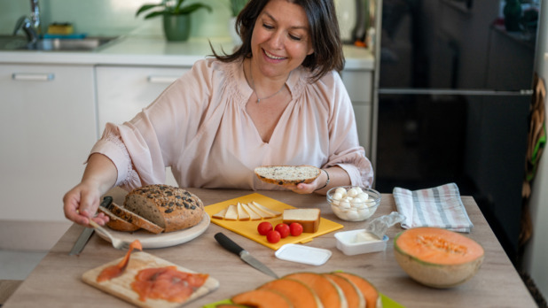 Vrouw eet gezonde en lekkere maaltijd met zalm aan keukentafel