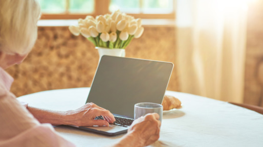 Vrouw met kop koffie achter de laptop