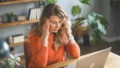 Vrouw zit overweldigd achter haar laptop