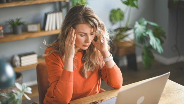 Vrouw zit overweldigd achter haar laptop