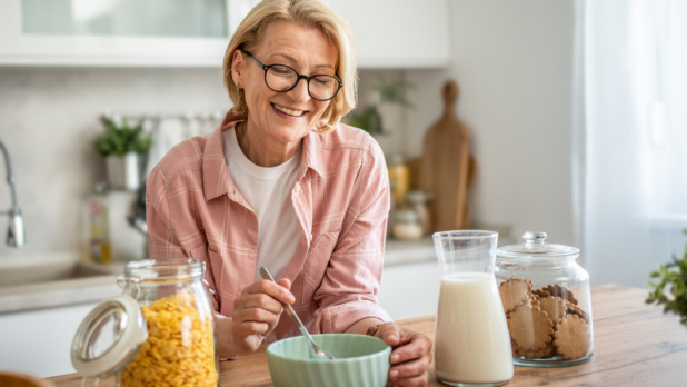 Vrolijke vrouw eet havermout in de keuken