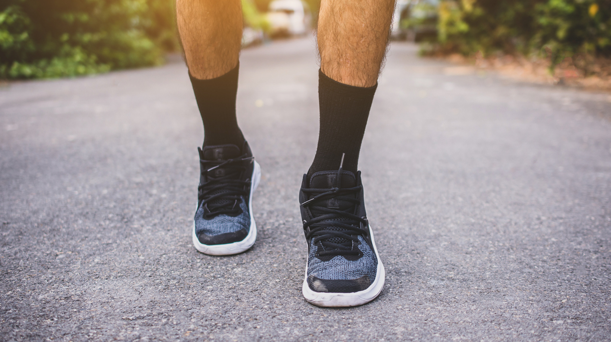 Man op gympen loopt op straat