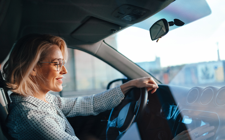 Oudere vrouw achter het stuur van de auto, lachend