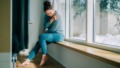 Vrouw met pijn zit op de vensterbank