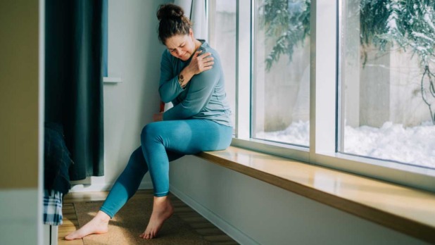 Vrouw met pijn zit op de vensterbank