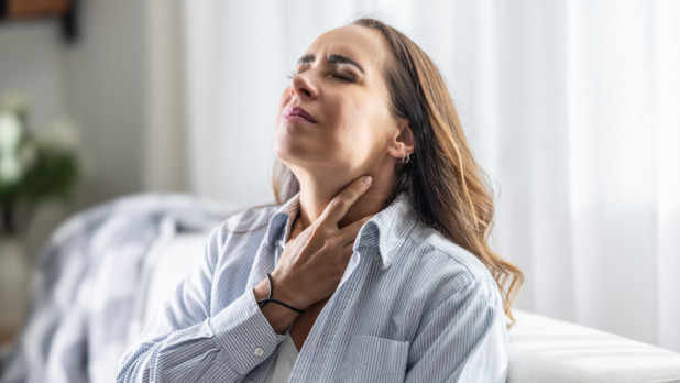 Vrouw heeft last van gallige reflux en grijpt naar haar keel
