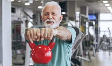 oudere man houdt kettlebell vast