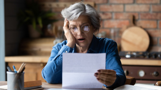 Oudere vrouw leest geschokt een brief