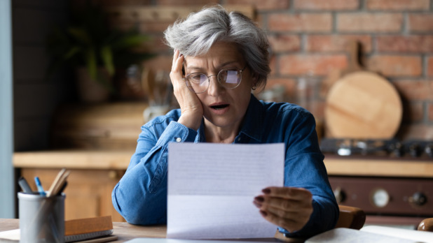 Oudere vrouw leest geschokt een brief