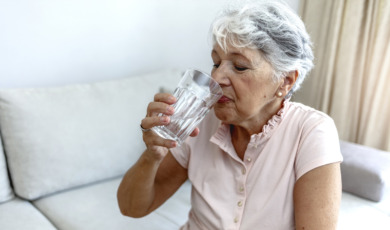 oudere vrouw drinkt water met warm weer