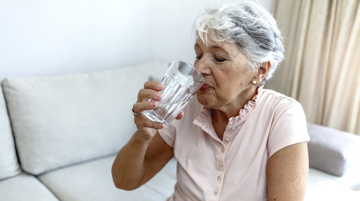 oudere vrouw drinkt water met warm weer