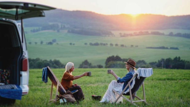 Twee vrouwen bij de ondergaande zon op vakantie met een kop thee