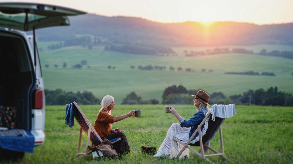 Twee vrouwen bij de ondergaande zon op vakantie met een kop thee