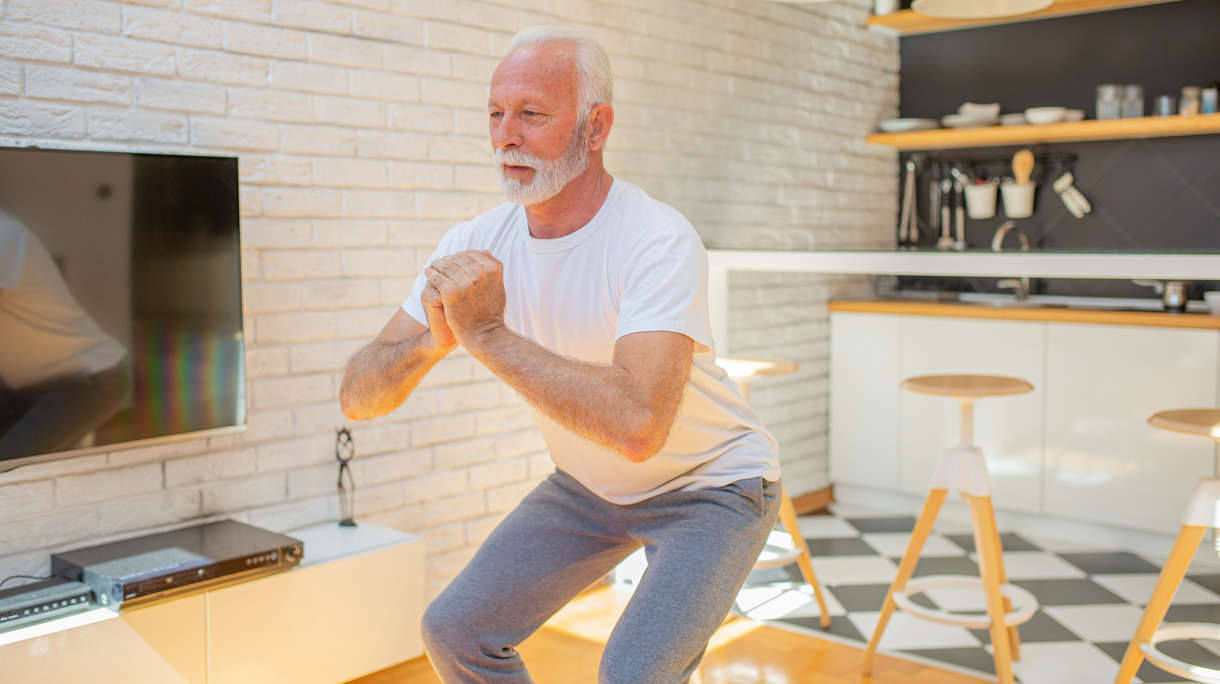 senior man doet squats thuis