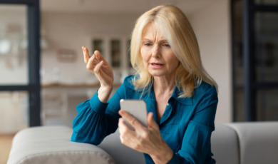 vrouw kijkt zorgelijk naar telefoon