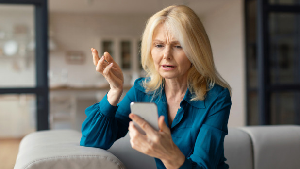 vrouw kijkt zorgelijk naar telefoon