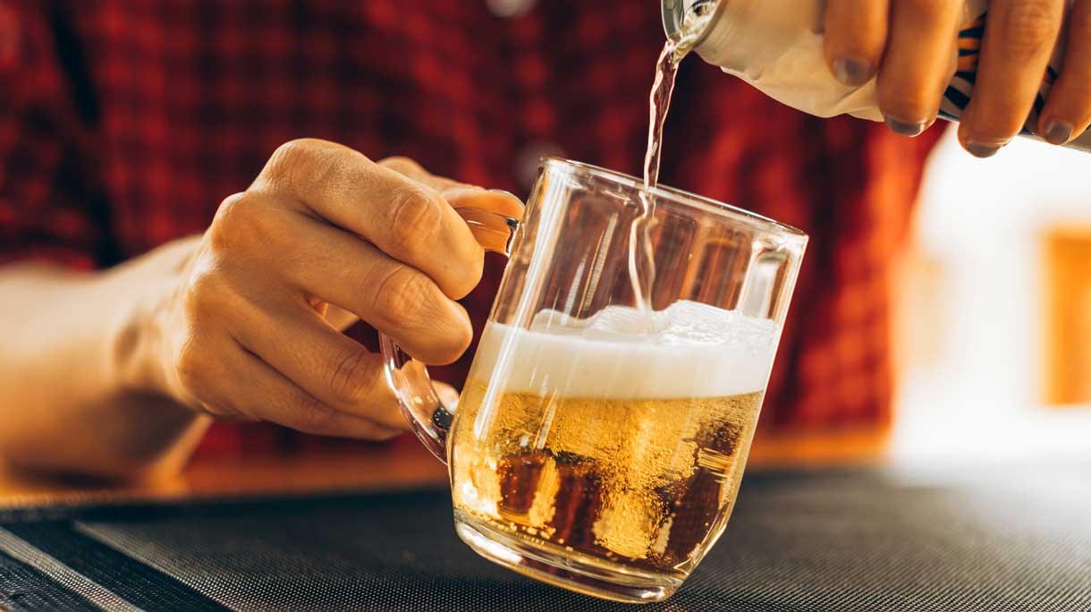 Vrouw schenkt een blikje bier leeg in een glas
