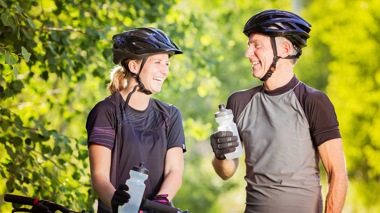 Man en een vrouw met fietshelm op de fiets tijdens fietstocht