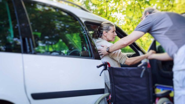 Man helpt gehandicapte vrouw uit auto