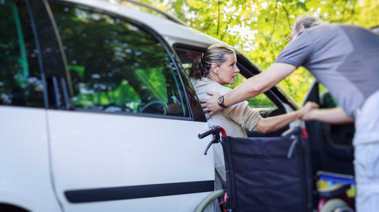 Man helpt gehandicapte vrouw uit auto