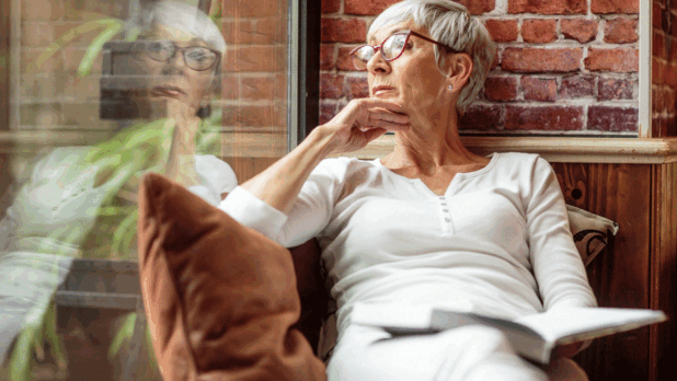 Vrouw met boek achter vensterraam