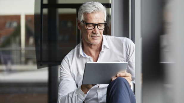Oudere man in de weer met zijn tablet