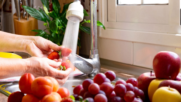 Vrouw wast aarbeien onder de lopende kraan in de keuken