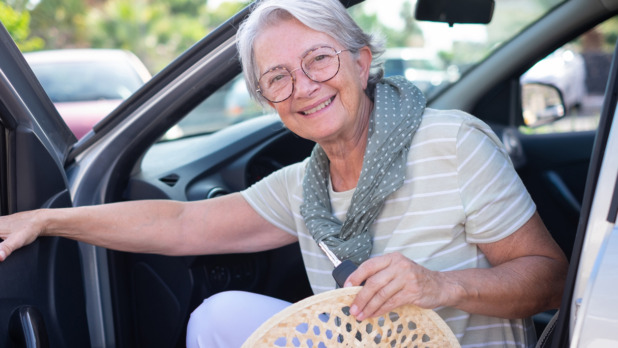 oudere vrouw stapt in auto op zomerse dag