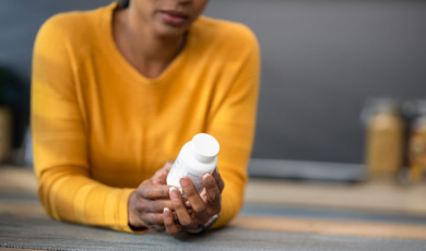Donkere vrouw kijkt naar potje vitamine D