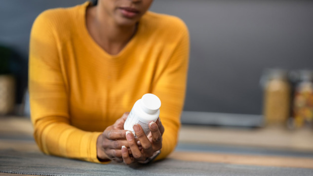 Donkere vrouw kijkt naar potje vitamine D