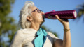oudere vrouw drinkt water in de zon