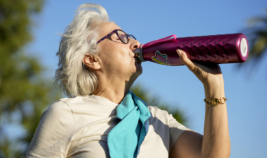 oudere vrouw drinkt water in de zon