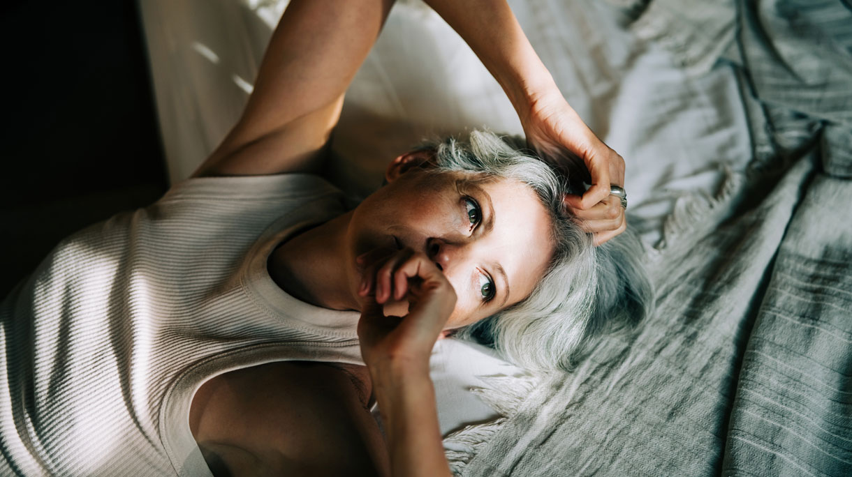 Vrouw ligt op bed en voelt zich niet goed