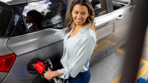 Vrouw is bezig met haar benzinetank vol te tanken bij tankstation