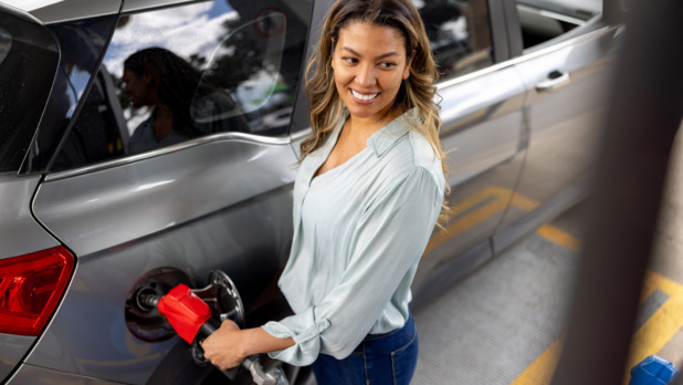 Vrouw is bezig met haar benzinetank vol te tanken bij tankstation
