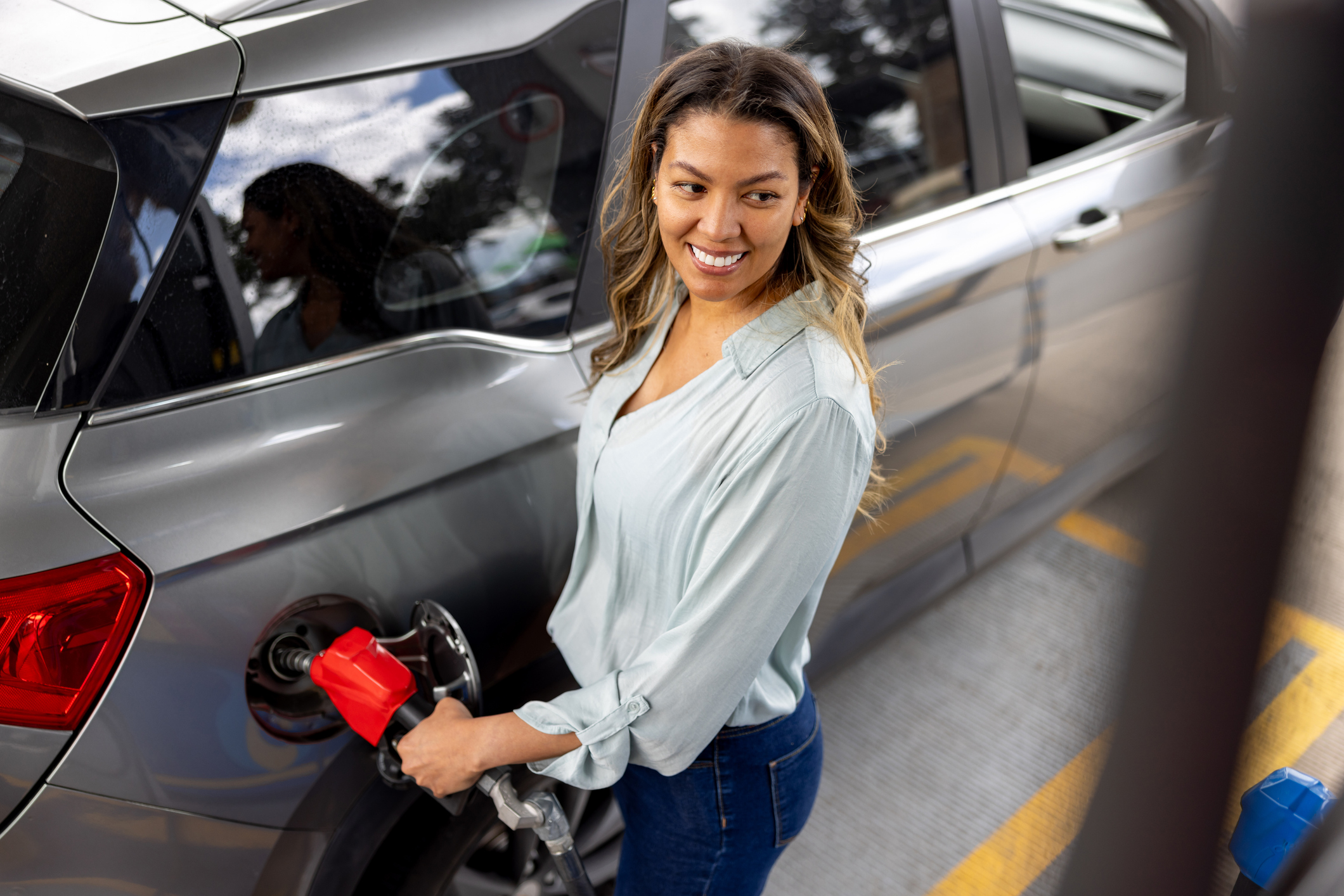 Vrouw is bezig met haar benzinetank vol te tanken bij tankstation