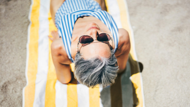 oudere vrouw met zonnebril op strand