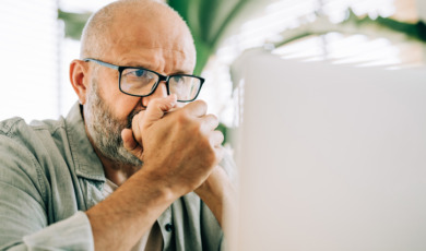 Man zit kniezend achter zijn laptop