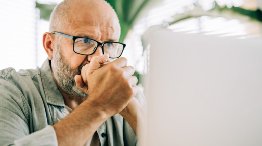 Man zit kniezend achter zijn laptop