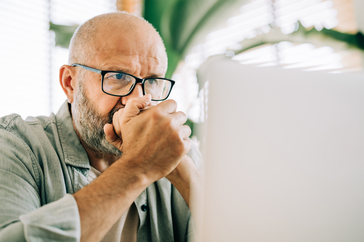 Man zit kniezend achter zijn laptop