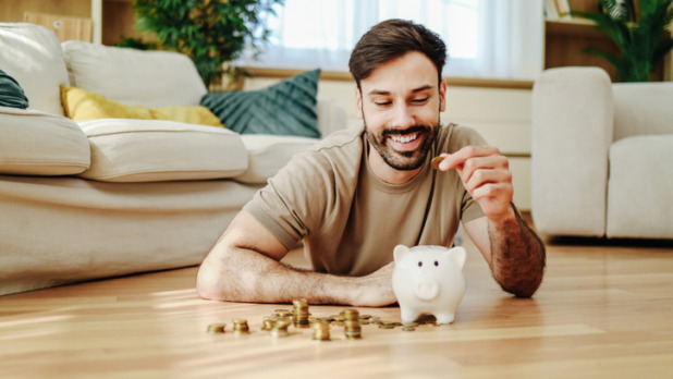 Man stopt geld in zijn spaarvarken