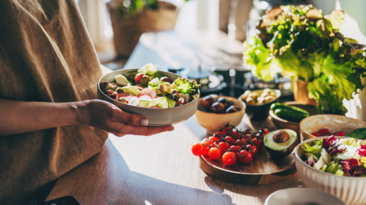 Vrouw met een bakje salade in haar hand, gezond eten